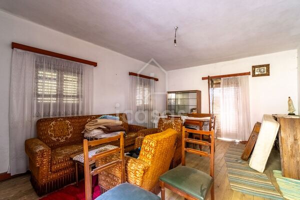 Sala mobilada, com sofás, mesa e janelas para o exterior
