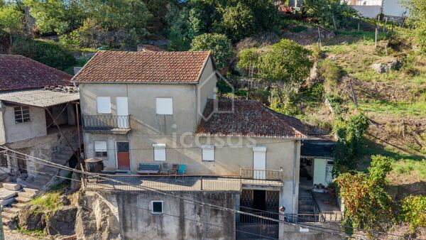 Fachada da moradia vista da rua, com o rés-do-chão da garagem e os dois pisos de habitação
